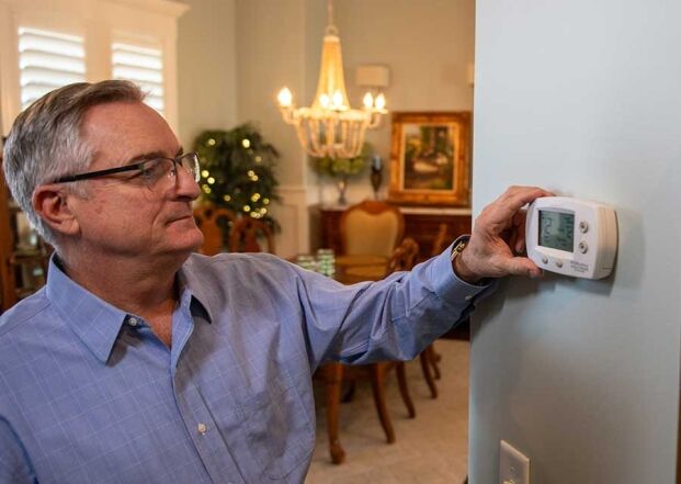 Homeowner adjusting thermostat indoors